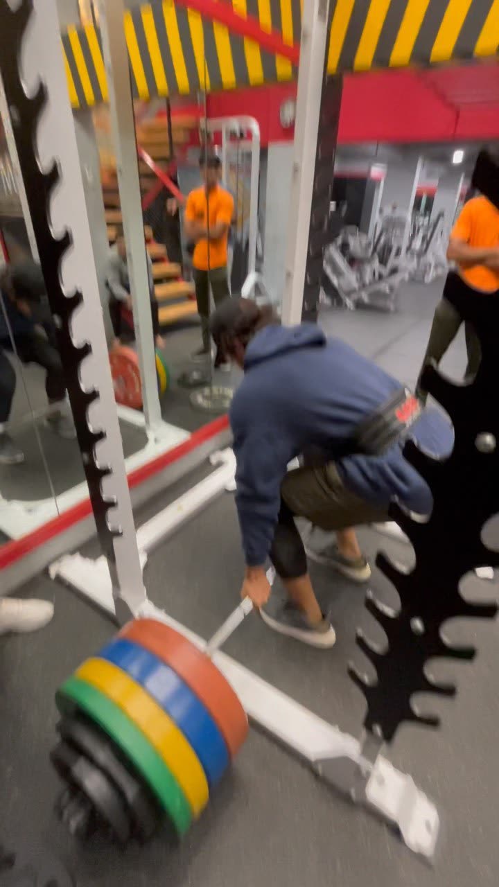 Elio loading weight plates onto a bar in the gym.