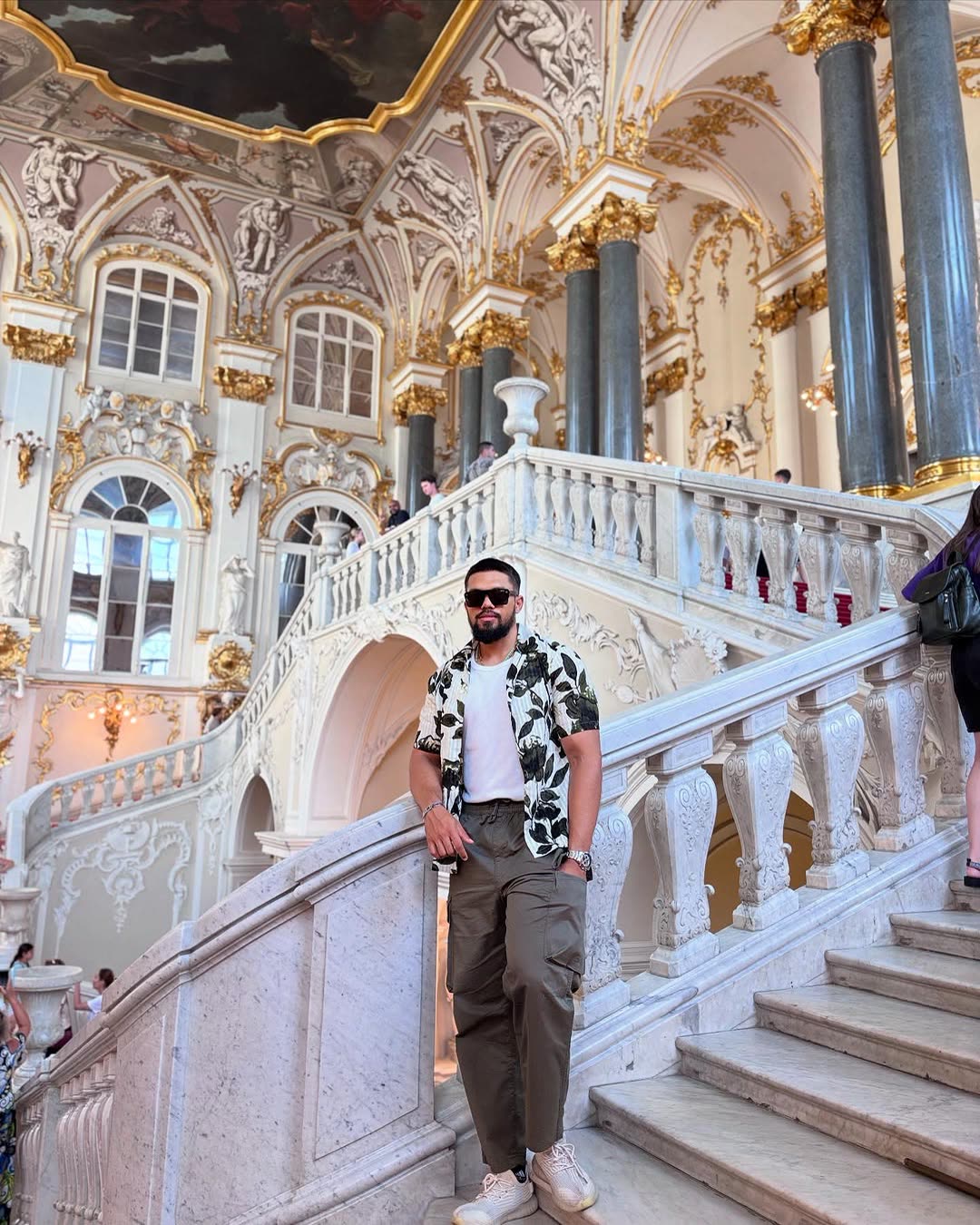 Elio on a white and gold palace staircase.