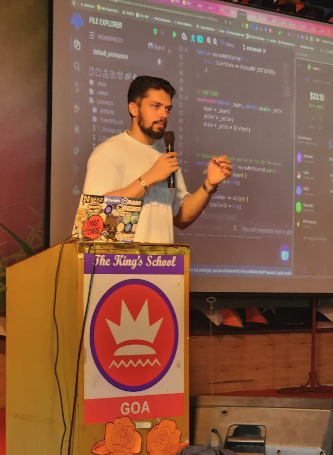 Elio teaching with a microphone in front of a projected smart contract.